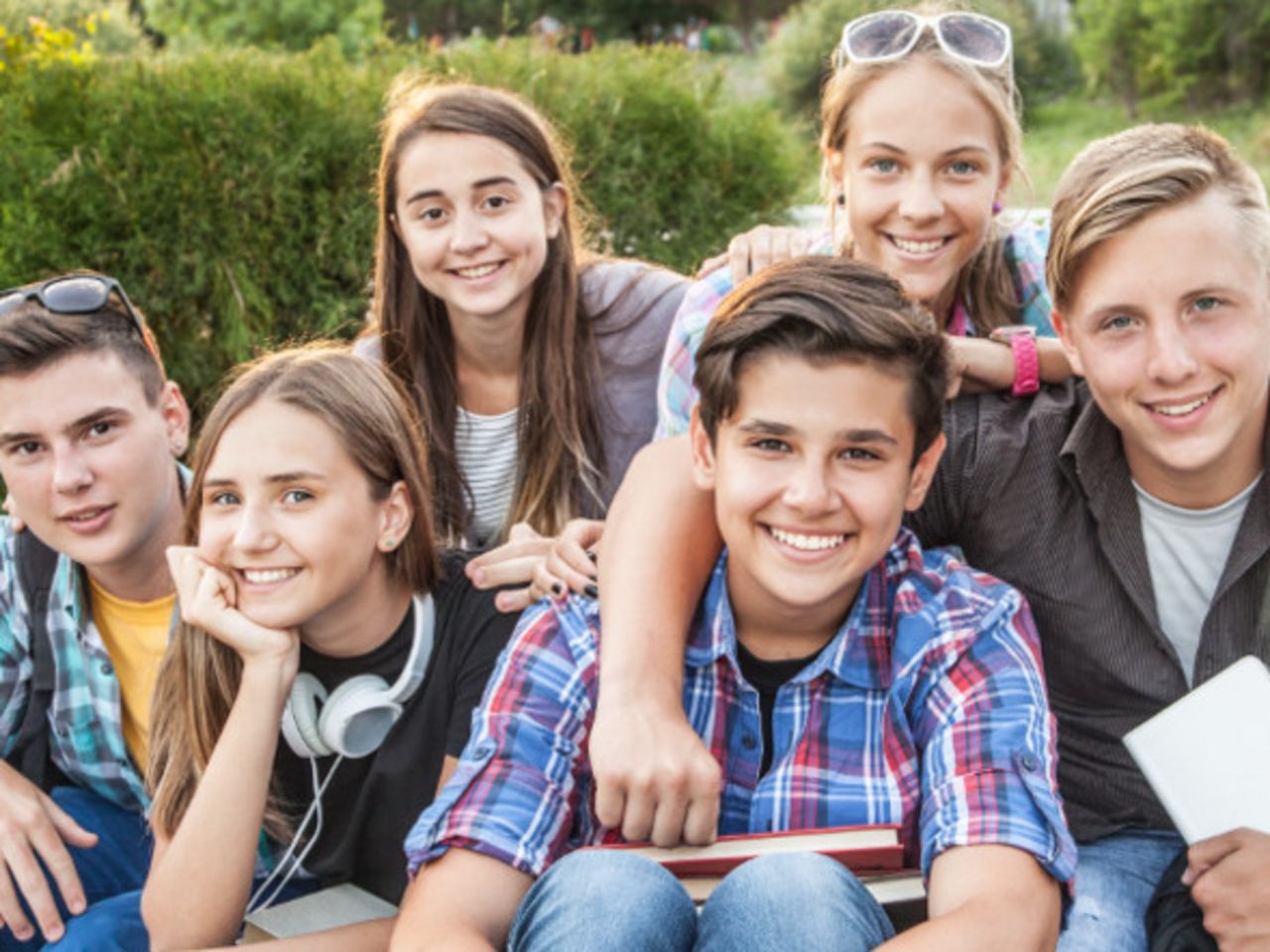 Beispielbild lachende Kinder und Jugendliche halten zusammen